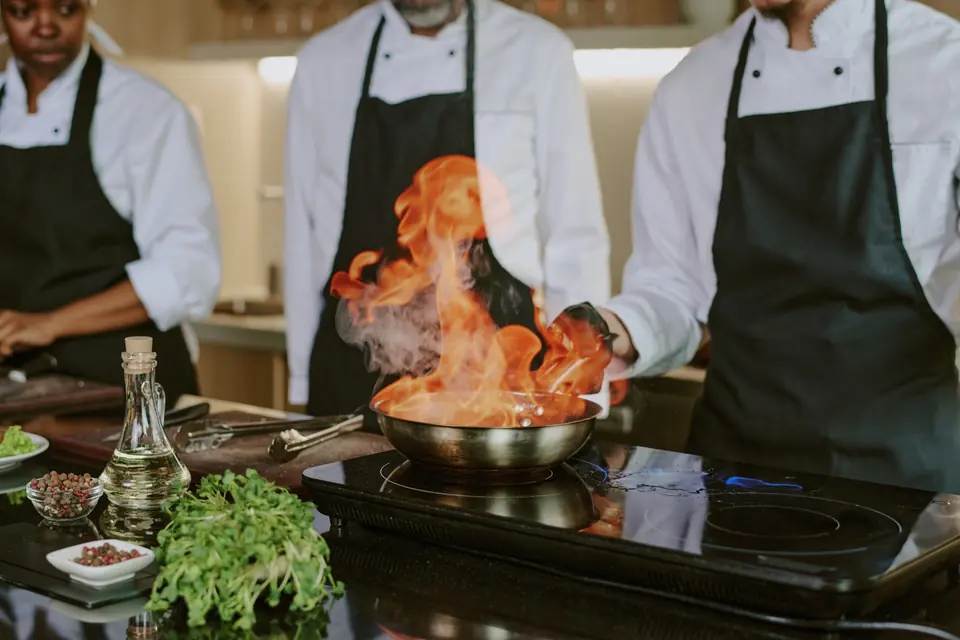 Cocineros flameando un platillo en la estufa